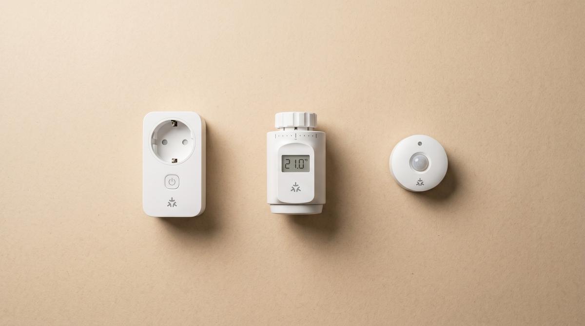 Drei weiße Smart-Home-Geräte in einer Reihe — Steckdose, Thermostat und Sensor — jeweils mit einem dezenten Matter-Symbol